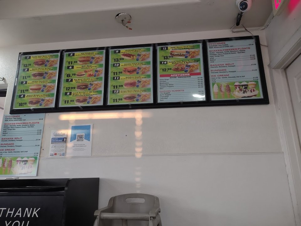 Menu board with burgers, fries, and sides.
